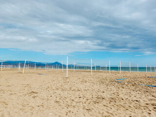 Empty Beach Volleyball Courts Facing the Sea Under a Cloudy Blue Sky
