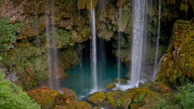 Drone extending from the impressive details of Yerk&ouml;pr&uuml; Waterfall pouring into the cave entrance to the forest and rocky atmosphere of the waterfall surrounded by mountains.