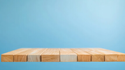 Fototapeta premium Wooden blocks are arranged in a straight line against a solid light blue background, creating a simple and clean composition that suggests stability and order.