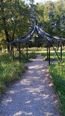 Rustic gazebo along a path in a lush garden, providing a serene retreat for relaxation and nature...