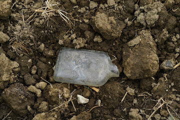 old discarded bottle in a field, throwaway society