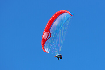 Tandem Paraglider flying in a blue sky	