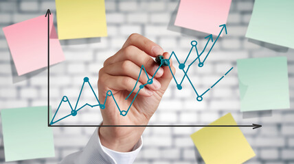 Hand drawing upward trending graph, teal line on white background, symbolizing growth, success, and progress in business planning