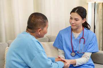 Asian senior female patient sitting on sofa receiving emotional support from young female physical...