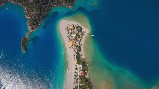 &Ouml;l&uuml;deniz's uniquely beautiful sand dune and turquoise lagoon, Waters where different shades of blue meet, thin white sand strip and lush green vegetation. Drone flies towards the forest area.