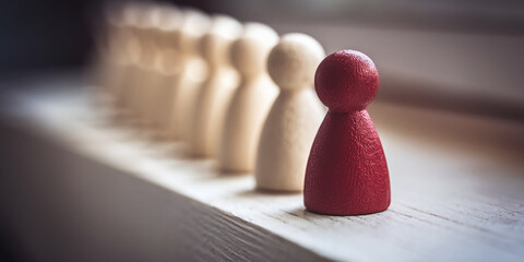 Close-up of red and beige wooden figures, one red figure stands out from a row of beige figures on a white surface, showcasing individuality and difference