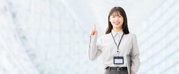 人差し指を立てて案内する笑顔の女性・ビジネスウーマン