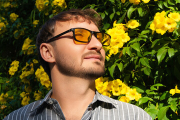 Eye wear fashion portrait of a handsome man with short brown hair and beard wearing sunglasses with...