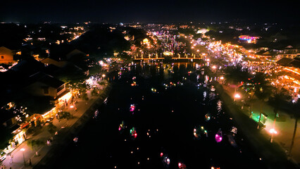 Illuminated boats drifting along thu bon river, glowing lanterns casting vibrant reflections during hoi an's full moon festival, capturing nighttime cultural celebration's enchanting essence