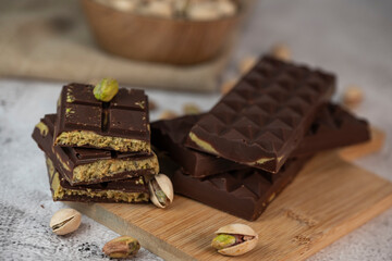 Gourmet chocolate mixed with crunchy kadaif pistachio pieces is beautifully presented on a wooden board, making a perfect treat in Dubai's culinary scene.