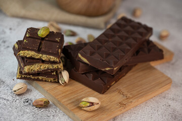 Gourmet chocolate mixed with crunchy kadaif pistachio pieces is beautifully presented on a wooden board, making a perfect treat in Dubai's culinary scene.