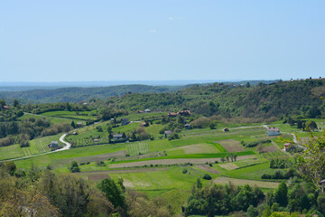 Obraz premium A picturesque view from Gornje Psarjevo in Croatia extends eastward over lush green fields and scattered houses under a clear sky