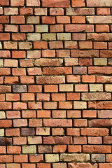 Fototapeta premium A textured brick wall displays various shades of red, brown, and beige in a classic running bond pattern