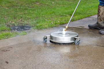 Man working on sidewalk, power washing and cleaning the concrete walk way