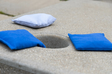 Closeup of cornhole bags on concrete board at park. Backyard game