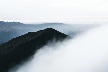 霧が漂う山の頂上に立ち、静寂な朝の光景を楽しむ瞬間を捉えた。