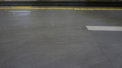 Cigarette ash floor with yellow disabled track at train station

