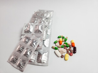 Assorted pills and capsules with blister packs on white background