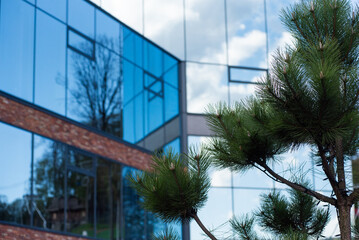 Contemporary glass building integrated into an eco-friendly environment. The sleek, reflective...