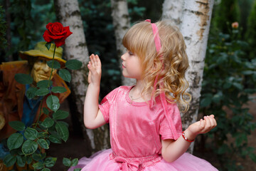 little girl in pink dress sniffing rose
