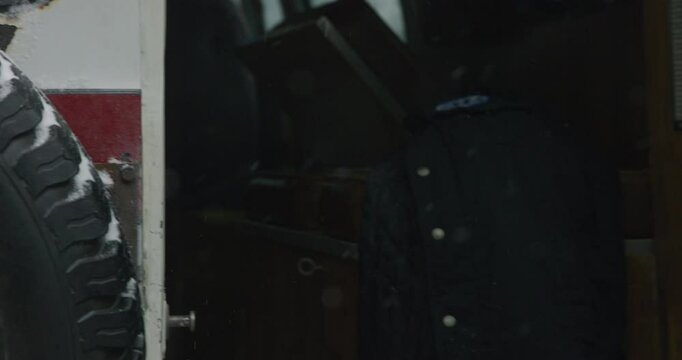 Closeup on person using a crow bar to open the back of an abandoned ambulance 