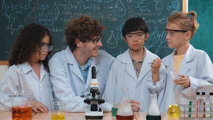 Skilled child hold tube while doing experiment while smart teacher explain and analyze chemical...