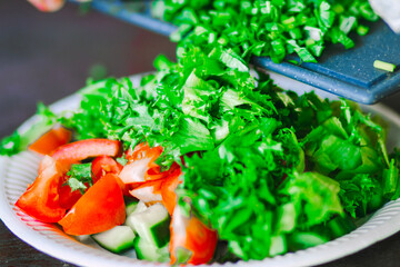 Close-up of fresh cucumber and tomato salad on a white plate placed on a natural wooden table, with focus on vibrant colors and texture of the vegetables.

