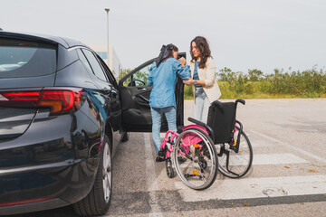 Assistant helping young woman with cerebral palsy into car - Caregiver supports female patient in...