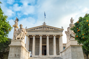 Academy of Athens with marble columns with sculptures of Apollo and Athena and tangerine trees in Athens, Greece. Popular landmark and travel destination