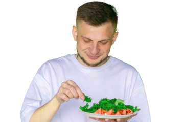 Smiling bearded man in a white t-shirt holding a plate of fresh vegetable salad with lettuce and tomatoes, on transparent background.
