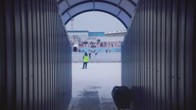 Boy service watches bandy game at stadium. View from under-tribune area.