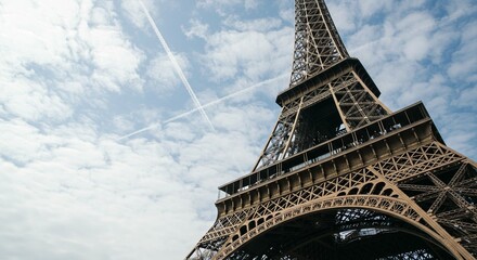 Upward view of the famous tower structure against a cloudy blue sky. Travel destination and...