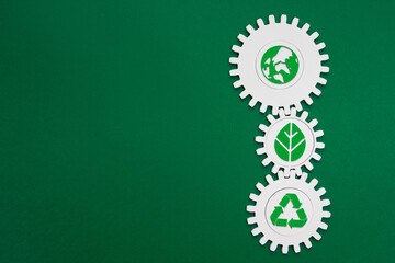Vertical Environmental Gears with Green Icons. Three interconnected white cogwheels with green...