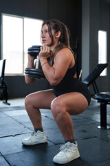 Athletic woman performing a goblet squat with a dumbbell at the gym, focusing on lower body strength and endurance