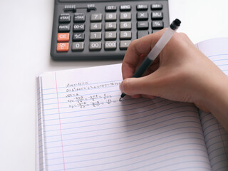 A student doing math in a notebook. Close up.