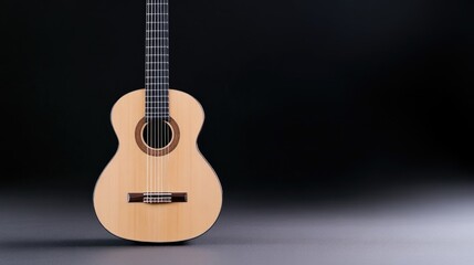Fototapeta premium Classical acoustic guitar standing upright against a dark studio background with soft lighting.