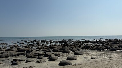 Expansive View of a Rugged Rocky Shoreline at Low Tide Meeting the Calm Blue Water and Clear...