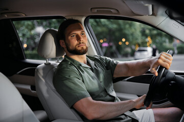 Man driving a car with a thoughtful expression in a modern interior