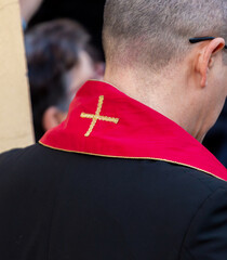 Priest wearing red stole with golden cross on the back