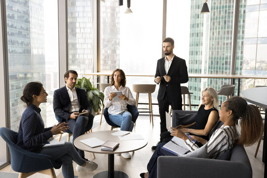 Business discussion. Busy diverse coworkers and team leader gather at modern office with panoramic windows engaged in brainstorm develop project startup discuss sales strategy create plans at workshop - Powered by Adobe