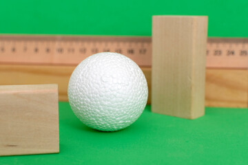 Still life with wooden blocks and a a plastic foam ball on green background	