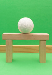 Still life with wooden blocks and a a plastic foam ball on green background	