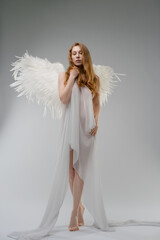 Red naked woman poses with angel wings and body art in studio setting