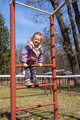 Obraz premium Happy Child Climbing on Playground Equipment Outdoors