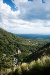 Mountain valley view with a winding road stretching through lush green hills. Captured from a high...