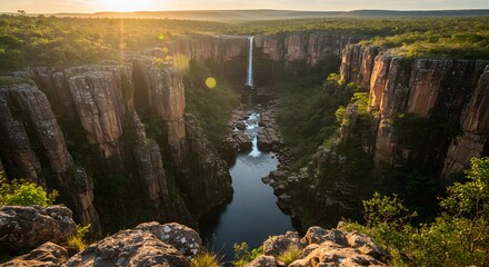 Spectacular aerial view of a powerful waterfall cascading down a canyon, bathed in sunlight.