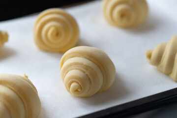 Close up of uncooked fluffy leavened traditional French croissants dough in a baking tray. It's a buttery, flaky pastry fold with butter in multiple layers, origin from Austrian.