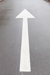 White arrow symbol in a straight direction on an asphalted avenue, transport concept