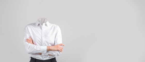 A headless figure dressed in a white shirt and dark pants stands with arms crossed in front of a...