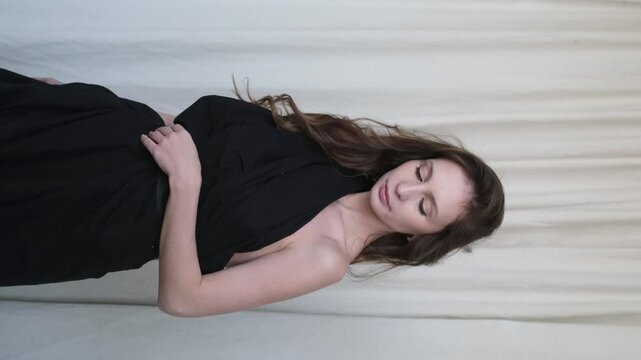 Portrait of a beautiful brunette with long hair on a fabric background in the studio. Beautiful natural woman posing for the camera